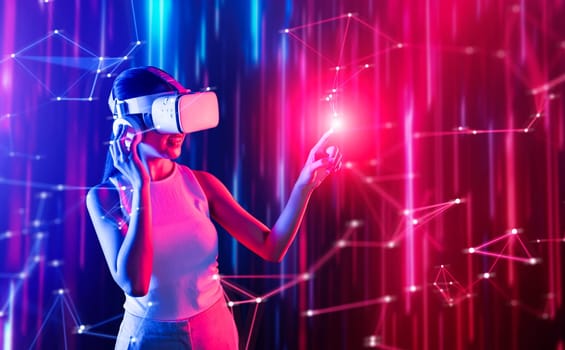 Smart female standing in cyberpunk style building in meta wear VR headset connecting metaverse, future cyberspace community technology, Woman use finger touching virtual reality object. Hallucination.