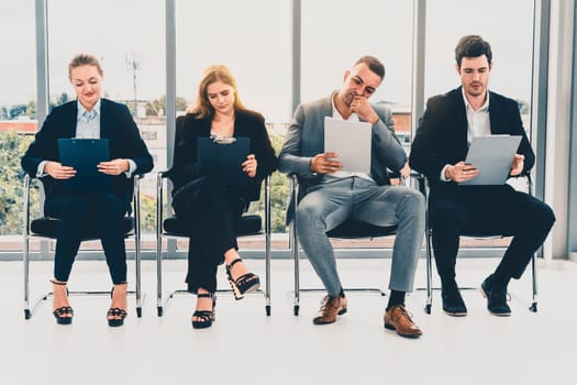 Businesswomen and businessmen holding resume CV folder while waiting on chairs in office for job interview. Corporate business and human resources concept. uds