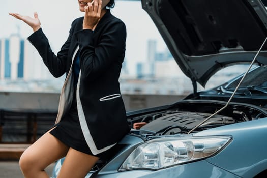 Young businesswoman whose car breakdown uses mobile phone to call for roadside assistance service. Travel and transportation vehicle problem. uds