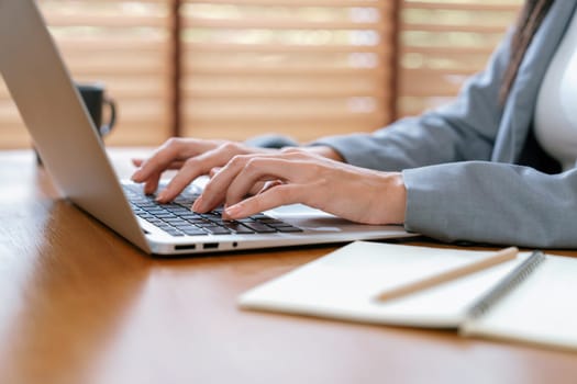 Businesswoman typing on laptop, working on business on workspace table. Young college student study or brainstorming strategic plan in office workplace for business success. Blithe