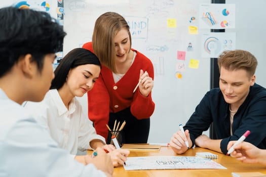 Happy cooperative multi-ethnic business group brainstorming discussion about marketing plan by using mind map in front of glass board with colorful sticky notes at meeting room. Immaculate.