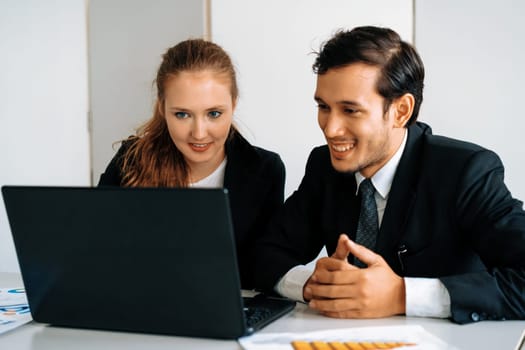 Happy businessman and businesswoman working using laptop computer at the office desk. Business teamwork concept. uds