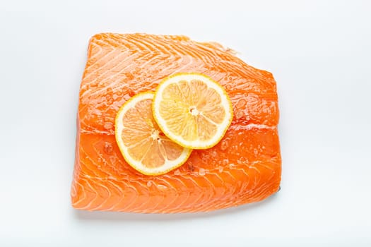 Fresh raw salmon marbled fillet isolated on white background with lemon and coarse salt, top view. Healthy nutrition and diet.