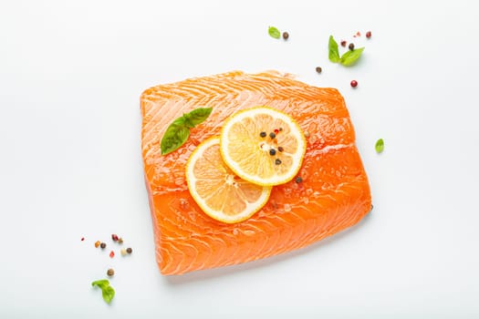 Fresh raw salmon marbled fillet isolated on white background with lemon, coarse salt, green herbs top view. Healthy nutrition and balanced diet.