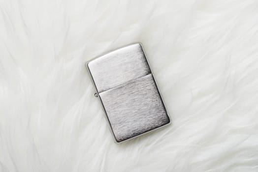 brushed chrome lighter with windproof isolated over white fur.