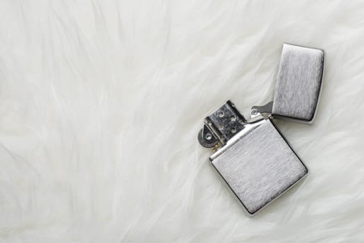 brushed chrome lighter with windproof isolated over white fur.