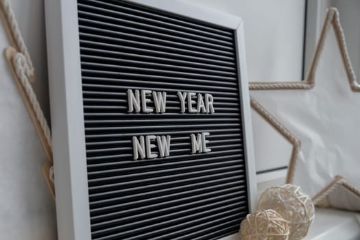 NEW YEAR NEW ME text on black letter board with cozy minimalistic handmade Christmas decor. New year aims resolutions. Low key festive Planning and setting goals concept