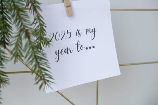 2025 IS MY YEAR TO text on white paper note on vision board with Christmas decor. New year aims resolutions. New me you concept visualizing dreams