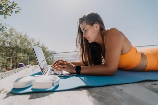 Digital nomad, Business woman working on laptop by the sea. Pretty lady typing on computer by the sea at sunset, makes a business transaction online from a distance. Freelance, remote work on vacation