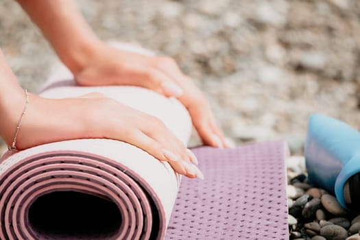 Young woman with long hair in white swimsuit and boho style braclets practicing outdoors on yoga mat by the sea on a sunset. Women's yoga fitness routine. Healthy lifestyle, harmony and meditation