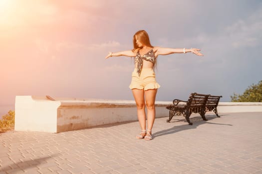 silhouette of a happy woman who dances, spins and raises her hands to the sky. A woman is enjoying a beautiful summer day.