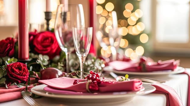 Festive table setting with cutlery, candles and beautiful red flowers in a vase.