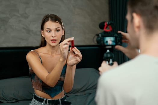 Man filming video on young woman making beauty and cosmetic tutorial video content for social media. Beauty blogger smiles to camera while showing how to beauty care to audience or follower. Unveiling