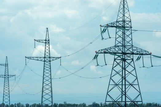 High voltage towers with sky background. Power line support with wires for electricity transmission. High voltage grid tower with wire cable at distribution station. Energy industry, energy saving.