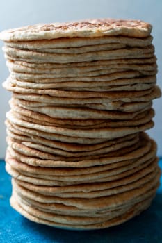 Flatbread lavash, chapati, naan, heap of tortilla on a blue background Homemade flatbread stacked