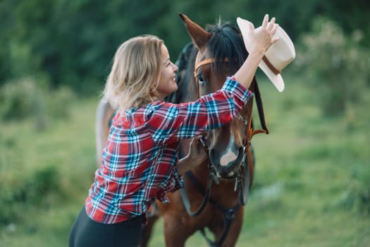 Happy blonde with horse in forest. Woman and a horse walking through the field during the day. Dressed in a plaid shirt and black leggings