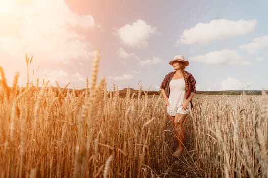 Woman farmer walks through a wheat field at sunset, touching green ears of wheat with his hands. Hand farmer is touching ears of wheat on field in sun, inspecting her harvest. Agricultural business.