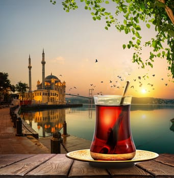 Tea and Ortakoy Mosque and Bosphorus bridge in Istanbul at sunrise, Turkey