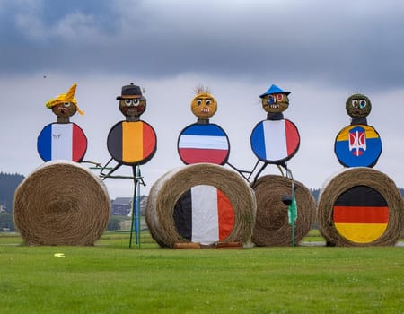 Funny figures made of straw bales on the background of a winter forest and field