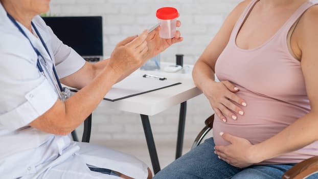 The doctor explains to a pregnant patient how to pass a urine test