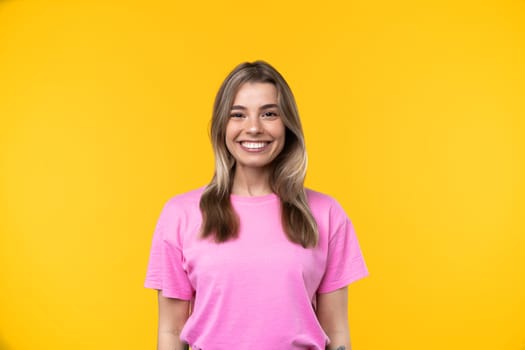 Happy emotions concept. Positive and beautiful young woman laughs poisitively looks aside with carefree face expression wears casual orange sweater isolated over yellow studio background.