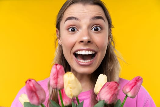 Happy emotions concept. Positive and beautiful young woman laughs poisitively looks aside with carefree face expression wears casual orange sweater isolated over yellow studio background.