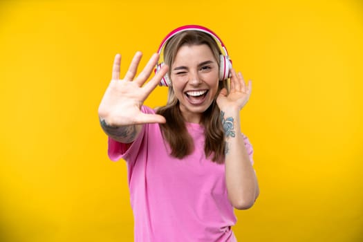 Happy emotions concept. Positive and beautiful young woman laughs poisitively looks aside with carefree face expression wears casual orange sweater isolated over yellow studio background.