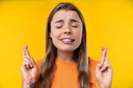 Happy emotions concept. Positive and beautiful young woman laughs poisitively looks aside with carefree face expression wears casual orange sweater isolated over yellow studio background.