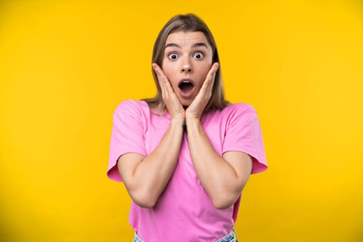 Happy emotions concept. Positive and beautiful young woman laughs poisitively looks aside with carefree face expression wears casual orange sweater isolated over yellow studio background.