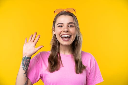 Happy emotions concept. Positive and beautiful young woman laughs poisitively looks aside with carefree face expression wears casual orange sweater isolated over yellow studio background.