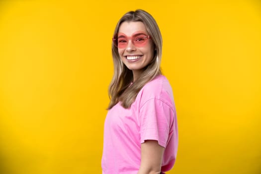 Happy emotions concept. Positive and beautiful young woman laughs poisitively looks aside with carefree face expression wears casual orange sweater isolated over yellow studio background.