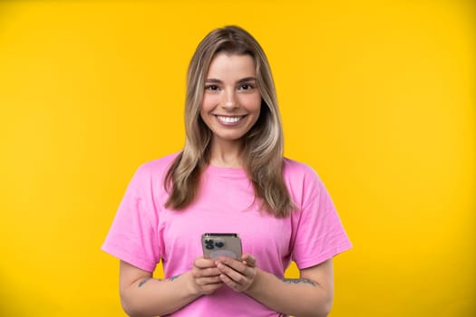 Happy emotions concept. Positive and beautiful young woman laughs poisitively looks aside with carefree face expression wears casual orange sweater isolated over yellow studio background.