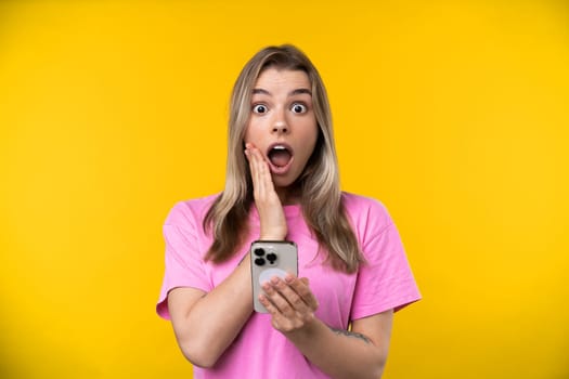 Happy emotions concept. Positive and beautiful young woman laughs poisitively looks aside with carefree face expression wears casual orange sweater isolated over yellow studio background.