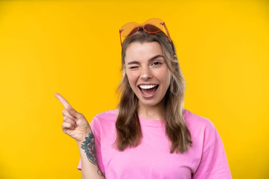 Happy emotions concept. Positive and beautiful young woman laughs poisitively looks aside with carefree face expression wears casual orange sweater isolated over yellow studio background.