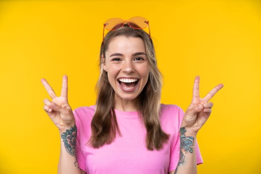 Happy emotions concept. Positive and beautiful young woman laughs poisitively looks aside with carefree face expression wears casual orange sweater isolated over yellow studio background.