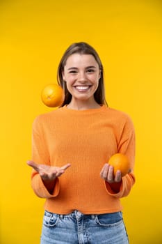 Happy emotions concept. Positive and beautiful young woman laughs poisitively looks aside with carefree face expression wears casual orange sweater isolated over yellow studio background.