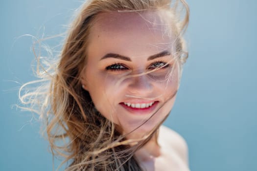 Portrait of a blond woman at the sea, a woman makes photos for memory from a trip to the sea to show to friends