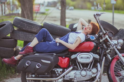 Beautiful girl mechanic on a motorcycle in a roadside workshop.