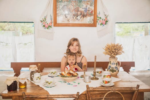 Sisters drink tea in an old Ukrainian hut.