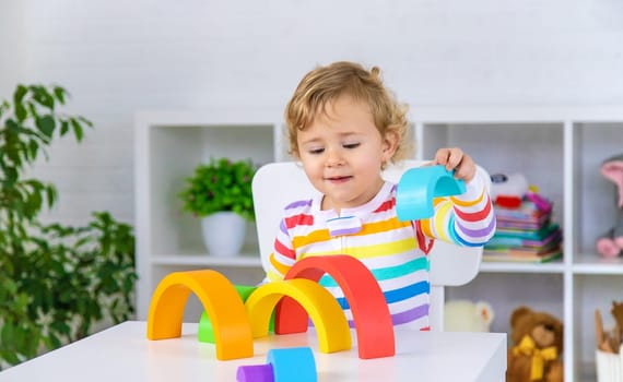 The child collects the constructor rainbow. Selective focus. Kid.