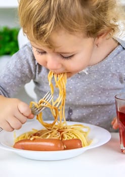 The child eats spaghetti lunch. Selective focus. Food.