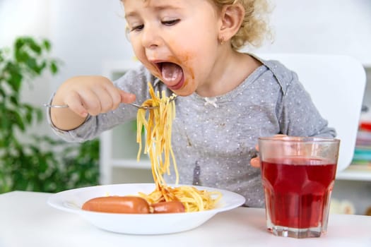 The child eats spaghetti lunch. Selective focus. Food.