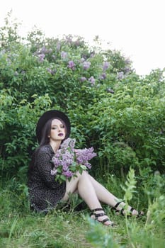 A fashionable girl with dark hair, a spring portrait in lilac tones in summer. Bright professional makeup