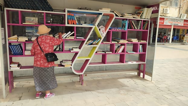 18 April 2024 Beersheva Israel, woman choosing books on a street bookshelf. High quality photo