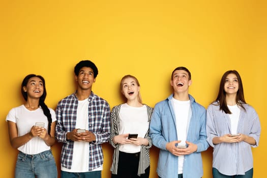 A joyful moment shared among a multiethnic group of teenagers, all looking upwards and laughing with genuine happiness.