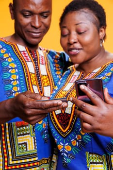 Couple holding debit card and smartphone while entering electronic banking information to pay for purchase. Black man and woman pair processing online payment on mobile website