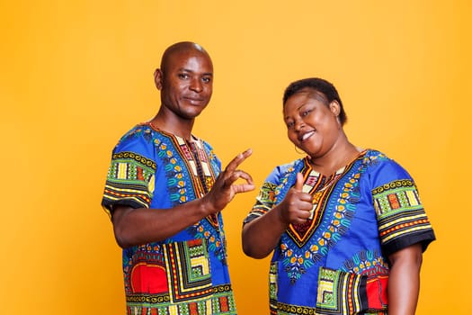 Smiling cheerful couple showing thumb up and ok symbol gesture portrait. Man and woman showcasing approval sign, giving positive feedback and looking at camera with carefree expression