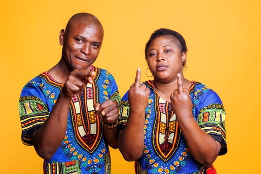 Black man and woman couple showing middle finger offensive gesture portrait. African american people showcasing provocative and rude behavior while looking at camera with negative expression