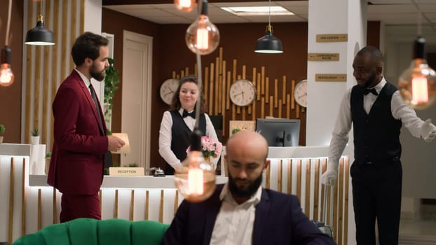 Hotel guest gaining access into room after doing check in process at front desk, taking key card from receptionist. Businessman travelling for work, international event. Handheld shot.