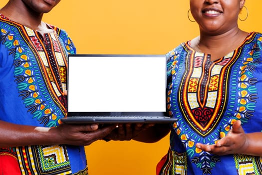 Man and woman promoting laptop blank screen with copy space for software advertising. African american couple showing with empty white display for app promo mockup closeup